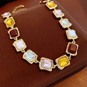 Close-up of vintage gold necklace with multi-colored square crystals on brown velvet box
