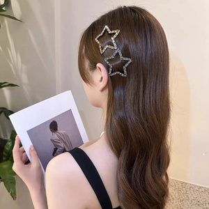 Detailansicht von zwei funkelnden Strass-Stern-Haarspangen in Gold und Silber im Haar