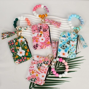 Flat lay of floral card holders with silicone bead wristlets and long tassels on white board