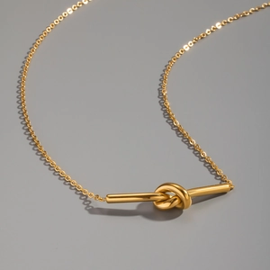 Détail du collier doré en acier inoxydable avec pendentif nœud et chaîne à maillons