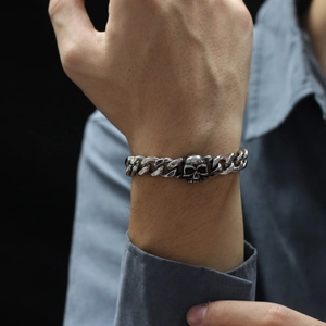 Close-up of a silver stainless steel skull Cuban link bracelet on a man's wrist