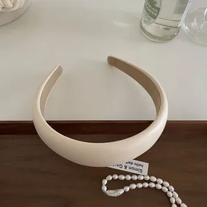 Detailed view of padded cream faux leather headband on a vintage wooden tray and pearl accents