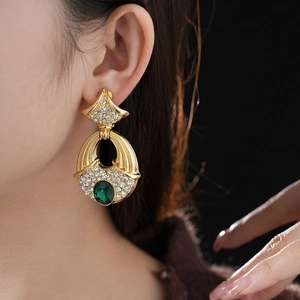 Detailed view of vintage gold earrings with green gemstones and sparkling rhinestones