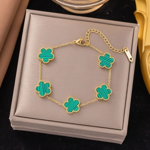 Detail of five-leaf green clover charms on a gold stainless steel bracelet with clasp