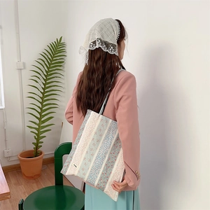 Sac fourre-tout floral en toile à rayures bleu et rose porté par un mannequin en studio