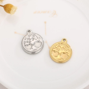 Round tree of life pendants in gold and silver finish with beaded edges on a plate