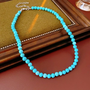 Close-up of vintage turquoise bead necklace with silver lobster clasp on green fabric