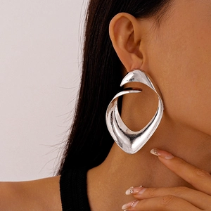 Close-up of a silver irregular geometric earring with a polished metallic finish on a model