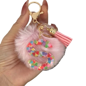 Pink pompom keychain with resin letter S and colorful heart sequins in golden finish