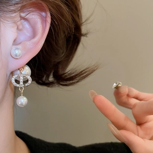 Detailed view of gold earrings with pearls and zircon-studded geometric links