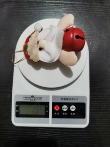 Detailed view of plush Santa Claus ornament weighing 19.5 grams on a digital scale