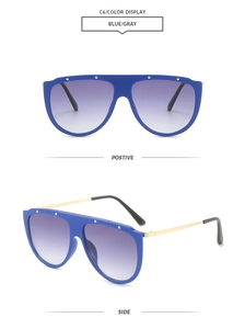 Detail view of large blue frame sunglasses with gold metal temples and gray gradient lenses