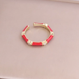 Detail of bamboo joint open ring in gold with red enamel and white zircon accents