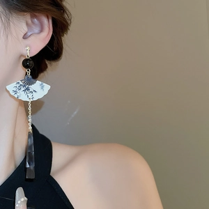Détail d'une boucle d'oreille en forme d'éventail avec motif bambou et résine grise