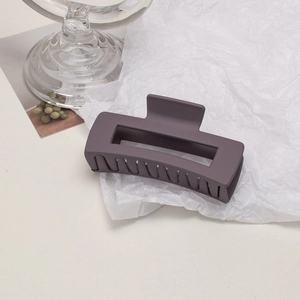Detail of large matte purple hollow hair claw clip with frosted texture on textured background