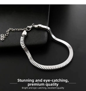 Macro shot of silver flat snake bone chain bracelet with lobster clasp on black texture