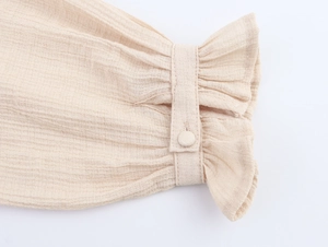 Detailed close-up of beige textured fabric cuffs with matching fabric-covered buttons