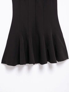 Close-up of the black dress hemline featuring soft wavy pleats and premium fabric texture