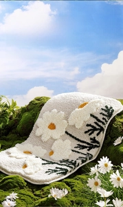 Close-up of floral tufted bathroom mat with 3D daisy pattern on green mossy background