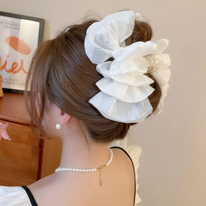 Detailed view of a large white organza bow hair claw clip for elegant bun hairstyles