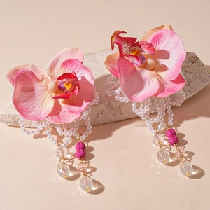 Pink orchid flower earrings with pearl tassels and crystals on a white stone background