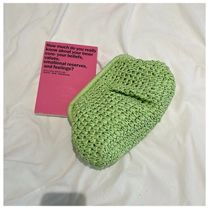 Close-up of light green woven straw clutch bag with texture detail on fabric