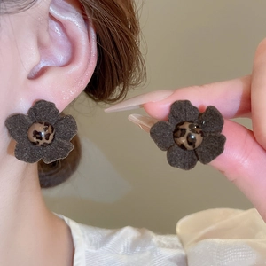 Detailed view of vintage fabric flower earrings with leopard print bead center on a model