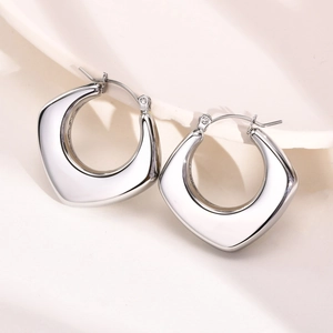 Close-up of silver hollow geometric earrings with polished mirror finish and U-shaped clasp