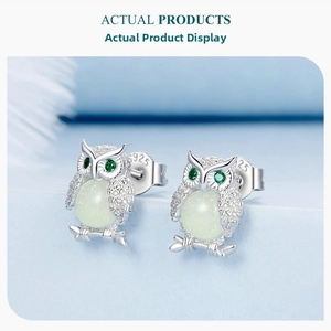 Close-up of S925 sterling silver owl stud earrings with green stones on a soft background