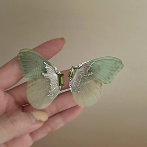 Vue détaillée de boucles d'oreilles papillon avec ailes en tulle vert et cristal émeraude