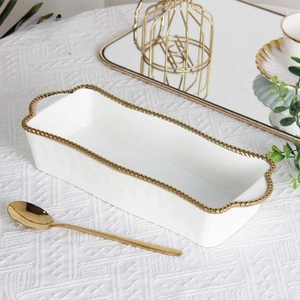 Macro detail of white ceramic tray with elegant gold beaded edges and handles