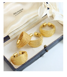 Detail of four-piece gold multilayer textured open rings in a vintage jewelry box