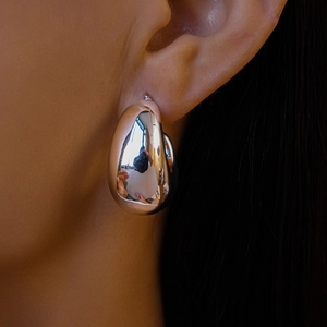 Detailed view of a silver water drop earring with mirror finish on a female model's ear