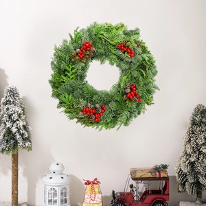 Detailed view of green Christmas wreath with pine cones and berries on a white wall