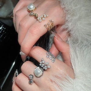 Detail of luxury zircon and multi-layer pearl rings on soft white faux fur background