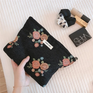 Macro detail of retro floral jacquard makeup bag with flower patterns and woven tag