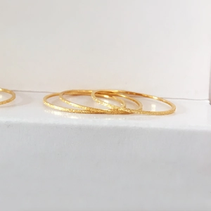 Macro view of four stackable thin rings with gold frosted sand finish surface
