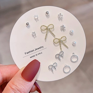 Detailed set of assorted stud earrings including bow, star, and pearl designs on card