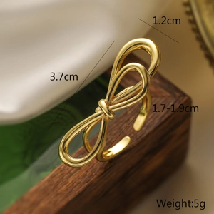 Detail view of 18K gold plated bow ring with 3.7cm span and 1.2cm width on wood