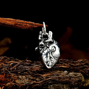 Vintage anatomical heart pendant in silver finish hanging on a rustic wood branch
