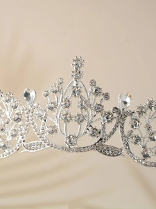 Detailed close-up of a silver bridal crown with intricate hollow patterns and clear rhinestones