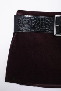 Détail du tissu en velours rouge foncé avec ceinture en similicuir croco et boucle argentée