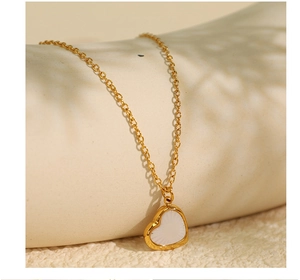 Détail macro d'un collier doré avec pendentif cœur et incrustation nacre sur support