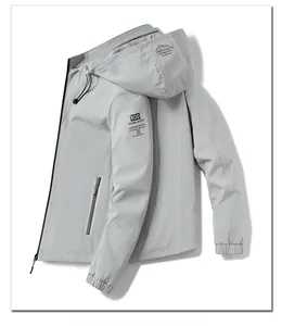 Detail of grey windproof hooded jacket showing zipper pocket and drawstring hood