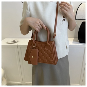 Close-up of caramel brown quilted handbag with logo embossing and a mini pouch detail