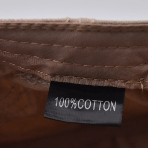Detail view of the 100% cotton material tag and stitching on a plaid newsboy cap