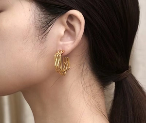 Close-up of geometric multi-layered gold C-shaped hoop earrings on a model