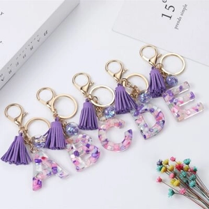 Detail of alphabet A-E resin keychains with purple dried flowers and gold metal lobster clasp
