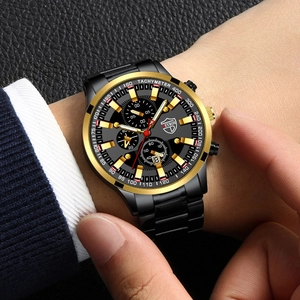 Detail of male hand adjusting black and gold stainless steel watch on leather background