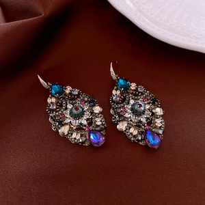 Macro detail of vintage style earrings with blue and purple teardrop gemstones on brown silk